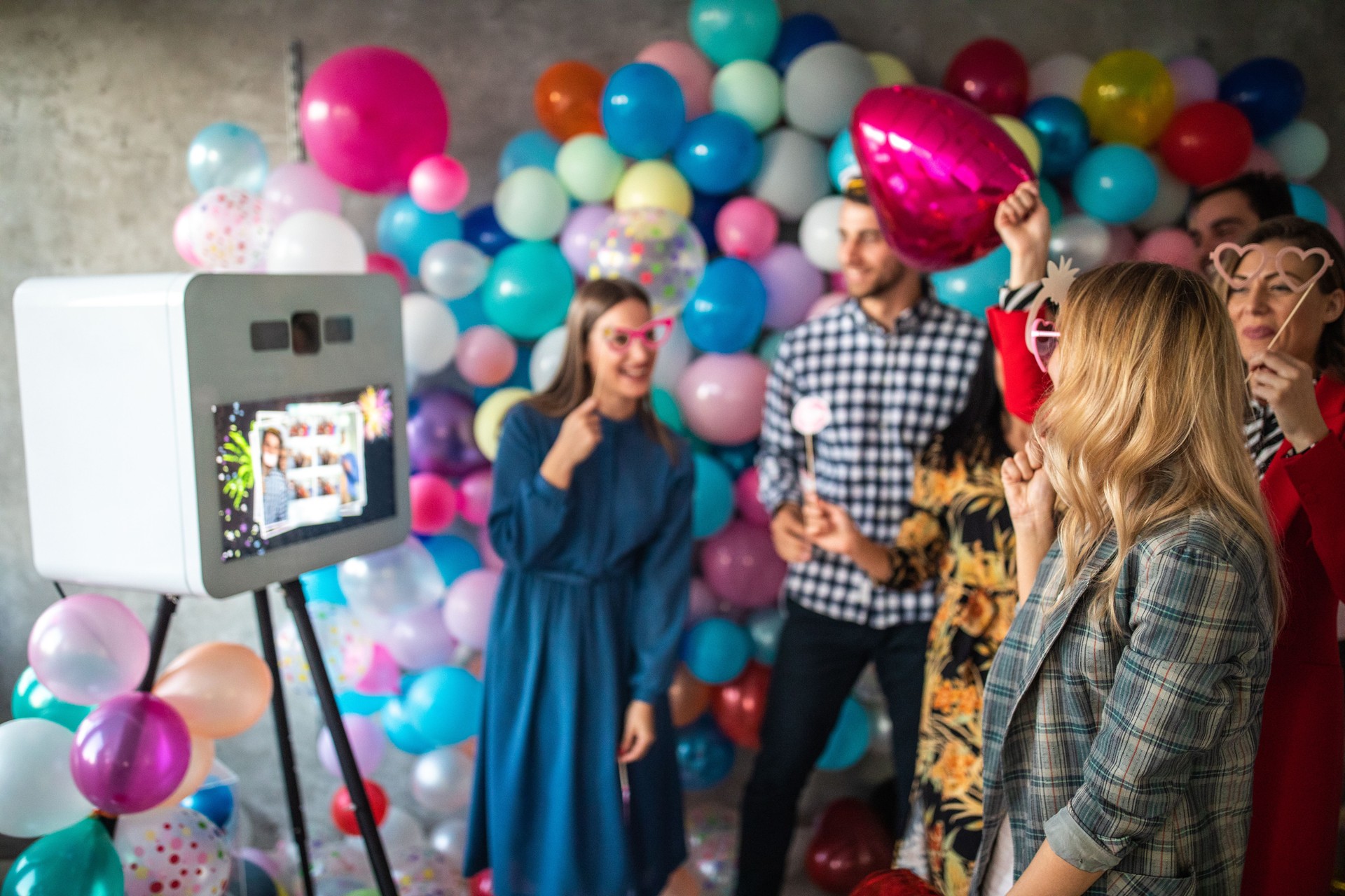 Friends having fun and taking photos using photo booth at home party